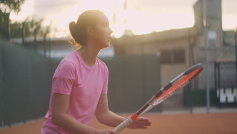 A-female-tennis-player-on-the-court-at-sunset-after-a-match-tired-looking-forward-and-concentrating-after-a-hard-game